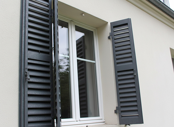 Persiennes métalliques sur une façade d'immeuble parisien exposées à la pollution urbaine