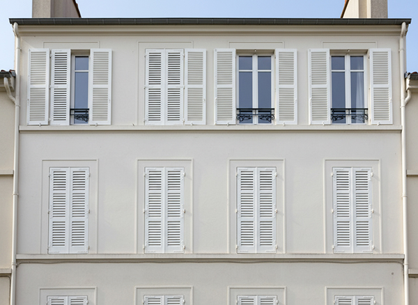 Traces de corrosion et écaillement de peinture sur des persiennes métalliques dégradées par la pollution